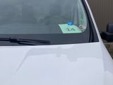 a white car with a green sticker on the windshield
