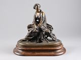 bronze statue of a woman sitting on a rock with a dog