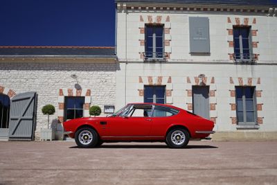 a red car parked in front of a large building