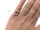 someone is holding a ring with an amethorate stone on it