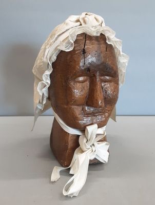 une tête en bois surmontée d'un foulard blanc
