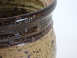 a close up of a brown vase on a white surface