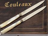 pair of ivory handled knives on a wooden box with the word courteauxx written on it