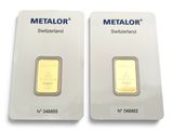 two gold bars are shown side by side on a white surface