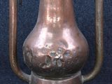 a large copper pot sitting on a stand on a blue surface
