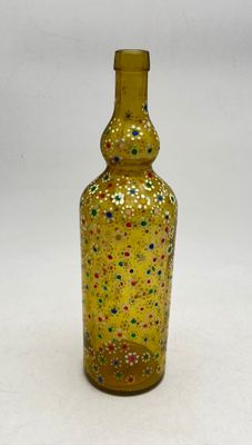 a yellow glass bottle with multicolored dots on it