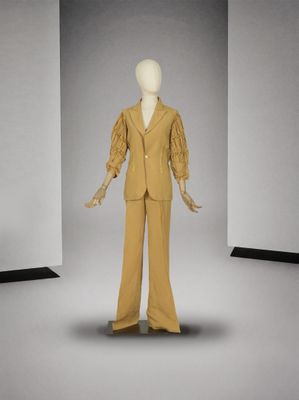 un mannequin vêtu d'un costume beige dans une pièce