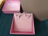 two pairs of pink earrings in a pink box on a blue carpet