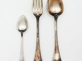 three spoons, a fork, and a spoon on a white surface