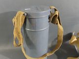 a metal container with a strap on it next to a canister