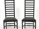 pair of black dining chairs with black leather upholstered seats