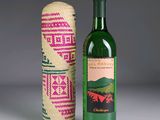 Des bouteilles de vin sont posées sur une table, à côté d'un cache-bouteille tressé.