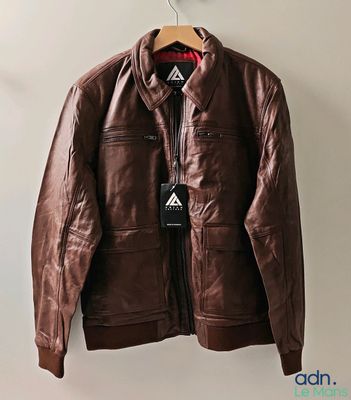 une veste en cuir marron suspendue à un cintre accroché au mur