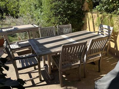 a wooden table and chairs on a patio in the sun