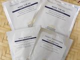trois paquets de masques pour le visage posés sur un plateau en bambou