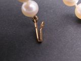 a pair of earrings with pearls on a black surface