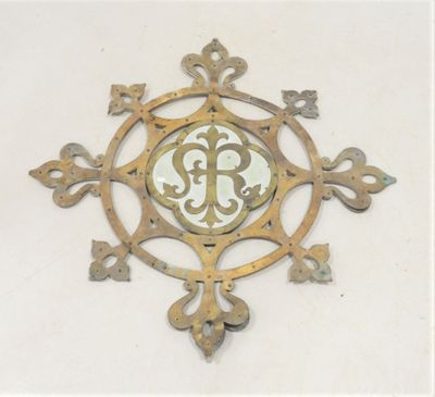 une horloge en métal sur laquelle figure un monogramme au centre