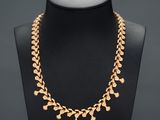 a gold necklace on a mannequin display with a black background