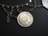 a silver coin on a chain next to a silver coin