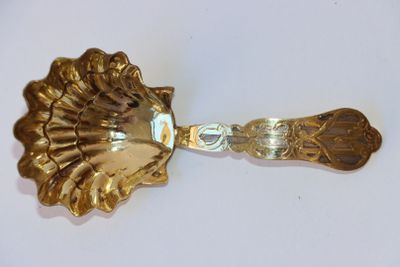 cuillère plaquée or ornée d'une tête de lion sur un fond blanc