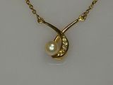 a close up of a gold necklace with a pearl on it