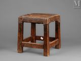 an old wooden stool with a square seat on a gray background