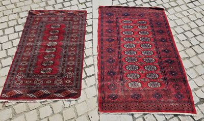 deux tapis rouges posés sur un sol pavé, devant un mur de briques