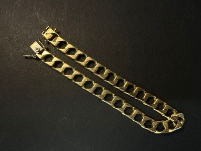 une paire de bracelets en or posés sur une surface noire