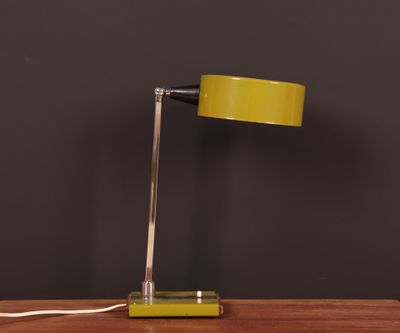 a yellow table lamp on a wooden table with a black wall behind it