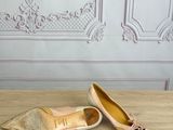 pair of gold shoes on a wooden table in front of a wall