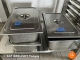 stainless steel food pans with lids on a stainless steel shelf