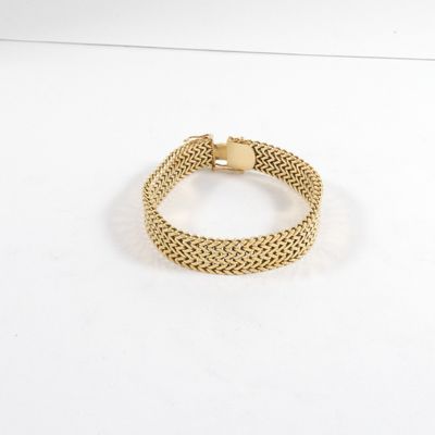 gros plan d'un bracelet en or sur une surface blanche