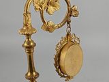 a gold clock that is on a stand with a clock on it