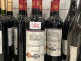 several bottles of red wine are lined up on a counter