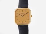 a close up of a gold watch on a black leather strap