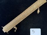 gros plan d'un bracelet en or sur une surface noire