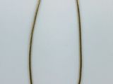 un collier en or avec une longue chaîne sur fond blanc