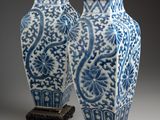 pair of chinese blue and white vases on stands on a gray background