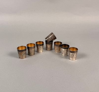 un ensemble de six serviettes et tasses argentées posées sur une surface blanche
