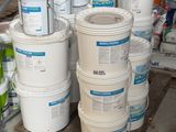 Plusieurs seaux de peinture sont empilés sur une palette dans un entrepôt