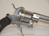 a silver revolver with a black handle on a clear stand