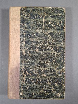 un vieux livre posé sur une table à côté d'un mur gris