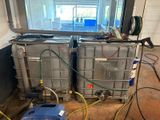two metal containers with hoses in a room