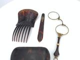 a hair brush, comb, scissors, and a case on a table