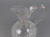 a clear glass pitcher with a handle on a table