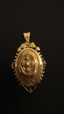 gros plan d'un pendentif en or sur une surface noire