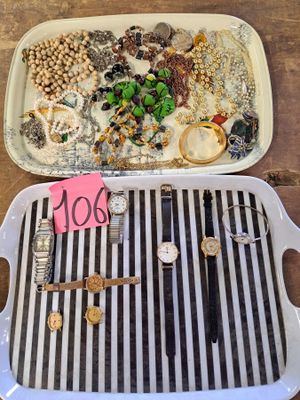 two trays of jewelry on a table with a note