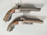 two silver pistols with wooden grips on a white surface