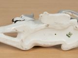 porcelain figurine of a cat laying on a bed with a cat on it ' s back