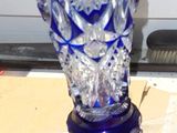 a blue glass vase sitting on a table next to a window